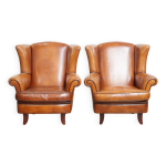 2 fauteuils à oreilles en cuir de mouton et passepoil noir 2 fauteuils à oreilles en cuir de mouton et passepoil noir