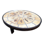 Table basse ovale vintage roger capron en céramique modèle aux herbiers à piétement en hêtre. Table basse ovale vintage roger capron en céramique modèle aux herbiers à piétement en hêtre.